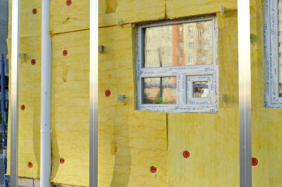 Vue d'une façade isolée en jaune avec fenêtre et poteaux métalliques