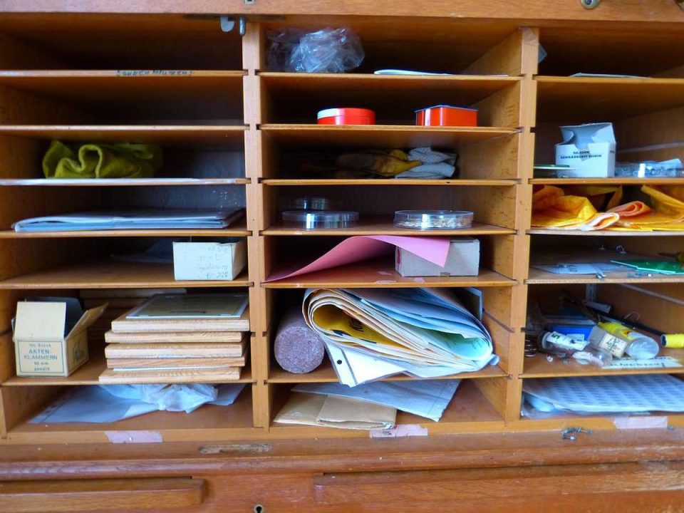 Un tiroir en bois plein de papiers, boîtes, rouleaux et fournitures de bureau