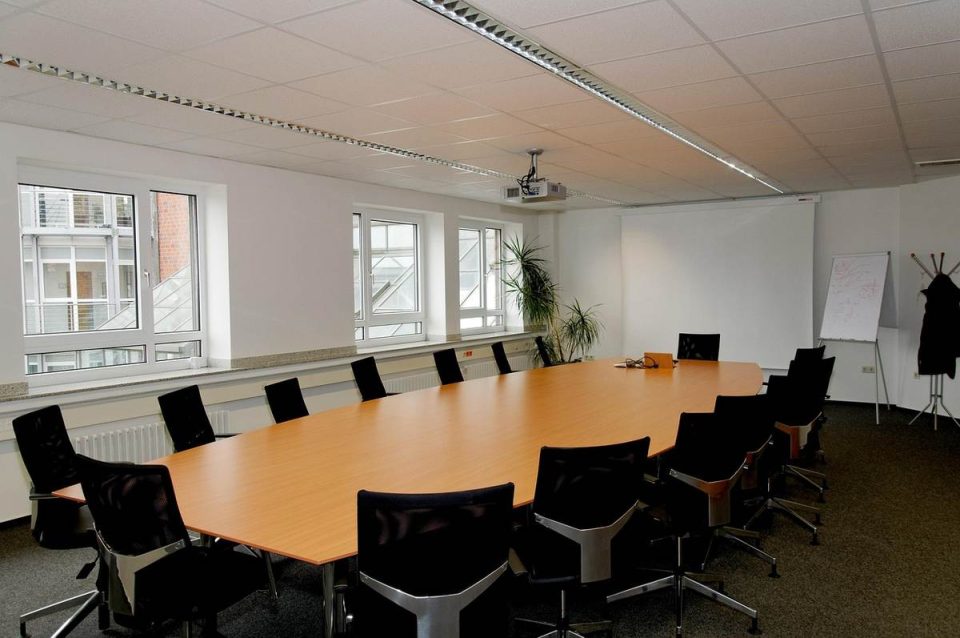 Salle de réunion moderne avec table ovale, chaises, fenêtres et tableau blanc