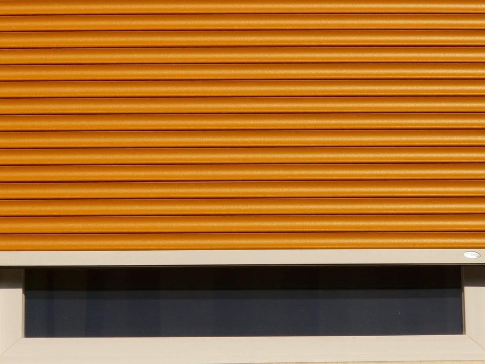 Volet roulant orange au-dessus d'une fenêtre à cadre blanc